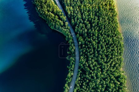 Luftaufnahme der Straße in grünen Wäldern und blauen Seen Wasser im Sommer Finnland