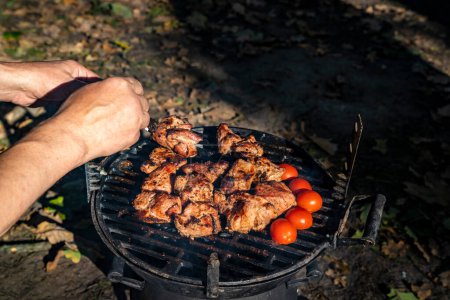 Téléchargez les photos : Homme cuisine de la viande sur le gril dans le jardin. - en image libre de droit