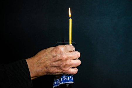 Foto de Un anciano, sus manos están arrugadas. Sostiene una vela de la iglesia, humo. - Imagen libre de derechos