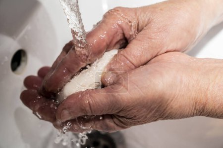 Téléchargez les photos : Un vieil homme se lave les mains avec du savon, des rides, du vieux. - en image libre de droit