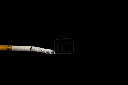 Foto de Fumar, un cigarrillo quemado. Daño a la salud. Fondo oscuro, ceniza. - Imagen libre de derechos