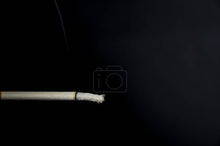 Photo for Smoking, burnt cigarette. Harm to health. Dark background, ash. - Royalty Free Image
