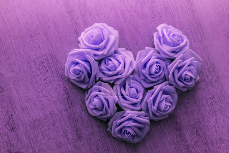 Téléchargez les photos : Coeur fait de fleurs de rose artificielles sur un fond sous un plancher en bois effet de couleur pourpre - en image libre de droit