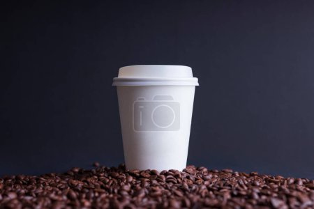 Téléchargez les photos : Tasse de café en papier parmi les grains de café torréfiés, sur fond noir - en image libre de droit