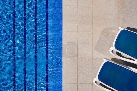 Foto de Detail of sun loungers al pool edge at a sunny day in resort - Imagen libre de derechos