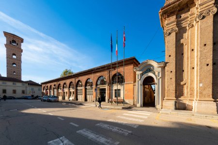 Photo for Carmagnola, Turin, Italy - November 05, 2022: piazza Alessandro Manzoni with entrance of the Town Hall and the fire brigade barracks and the bell tower of the church of saints Peter and Paul - Royalty Free Image