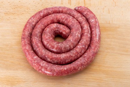 Photo for Rolled raw sausage on wooden cutting board in top view - Royalty Free Image