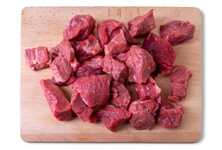Raw beef diced for stew on wooden cutting board isolated on white with clipping path, top view