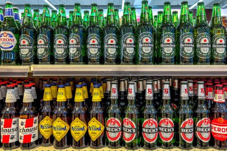 Téléchargez les photos : Italie - 11 janvier 2024 : Bière dans des bouteilles en verre de différents types et marques exposées sur des étagères à vendre dans un supermarché italien. Heineken pur malte lager et becks bière et Messina bière. - en image libre de droit
