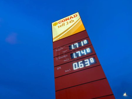 Photo for Savigliano, Italia - 26 gennaio 2024: Conad self 24h logo sign with fuel price display on totem in a fuel distribution plant of the Italian supermarket Conad in night view at blue hour after sunset - Royalty Free Image