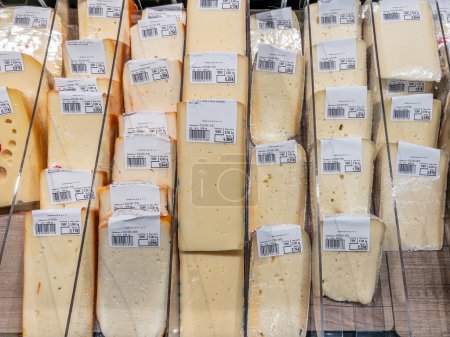 Foto de Italia - 04 de marzo de 2024: Fontina y fontal rodajas de queso italiano y otros tipos exhibidos a precio en nevera para la venta en el supermercado - Imagen libre de derechos