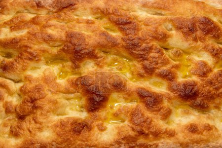 Focaccia with olive oil in full frame as background texture, flatbread golden crust texture - pattern