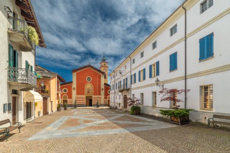 Sanfront, Cuneo, Italia - 03 de mayo de 2024: Piazza Ferrero pavimentada con pórfido y losas de piedra con la iglesia parroquial de San Martino 