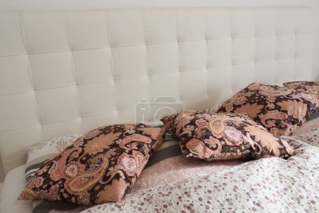 Téléchargez les photos : Oreillers décoratifs roses sur le linge de lit. Lit double nuptial avec oreillers et couette épaisse en plumes. Conception de chambre. Tête de lit blanche douce. Intérieur avec meubles et literie - en image libre de droit