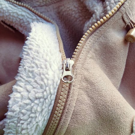 Photo for Suede outerwear. Overhead loops for buttons. Open zipper. Beige faux suede with sheepskin on the fold of a demi-season garment. seams in the material. Clothing industry and fashion - Royalty Free Image