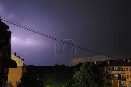 Photo for Thunderstorm at night over the city. Flashes of lightning and low clouds. Thunder and lightning. Natural element, climate change and weather forecast concept. Discharge of electricity in the sky - Royalty Free Image