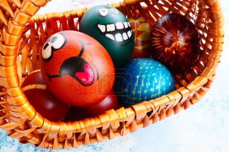 Photo for Easter eggs painted in different colors with painted laughing faces. Funny grimaces with eyes tongue and big white teeth. Scary face for Halloween. Emoticon for Easter Wicker basket. White background - Royalty Free Image