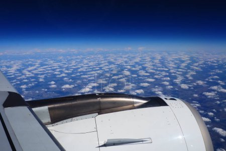Téléchargez les photos : Moteur d'avion et aile à la frontière de l'atmosphère et de l'espace. Le bord de la troposphère. Horizon sur la Terre. Vols, voyages et tourisme. Vue depuis une fenêtre ou un hublot. Nuages et ciel bleu - en image libre de droit