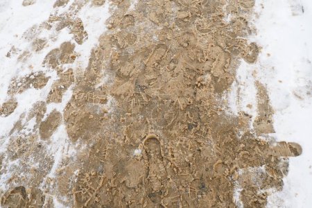 Photo for Many footprints of shoes and boots on the snowy pavement. Winter in the city. Wet weather and freezing temperatures. Weather forecast. Ice, white snow and muddy tracks with clay on the road - Royalty Free Image