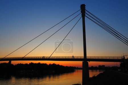 Photo for Pedestrian Bridge of the Saint Irinej over Sava river. Longest Pedestrian-Cycling Bridge in Europe Located Between Sremska Mitrovica and Macvanska Mitrovica. Twin towns on the opposite coasts. Sunset - Royalty Free Image