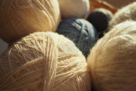 Photo for White, beige and blue woolen and acrylic threads wound into a ball or skein. Several skeins of light yarn in a basket. Knitting as a hobby. A clew of thread - Royalty Free Image