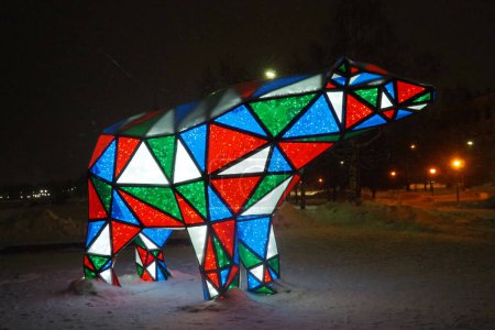 Photo for Bear garland. Multi-colored sparkling electric New Year Christmas bear on snow at night. Installation figure, architectural form for decorating streets on holiday. Red, blue, green, white triangle. - Royalty Free Image