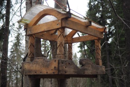 Hanging homemade feeder or platform for feeding birds and squirrels in winter and spring during hungry times. Feeders for birds and squirrels in a forest or city park
