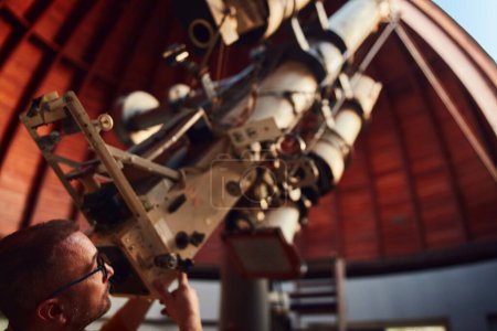Foto de Astrónomo con un gran telescopio astronómico en el observatorio haciendo investigación científica de objetos espaciales y celestes. - Imagen libre de derechos