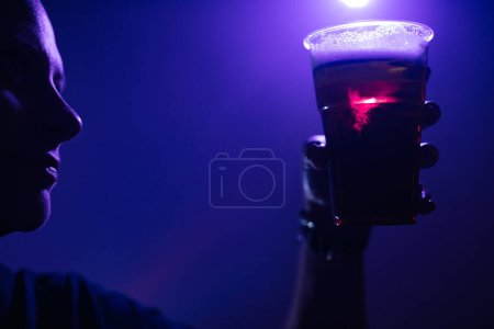 Téléchargez les photos : Personne tenant une tasse de bière en plastique dans la boîte de nuit. - en image libre de droit