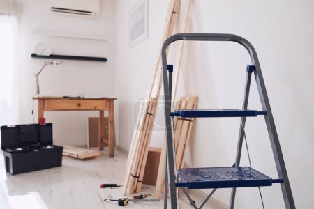 Téléchargez les photos : Table en bois rustique et matériel pour les nouvelles étagères dans un appartement moderne. - en image libre de droit