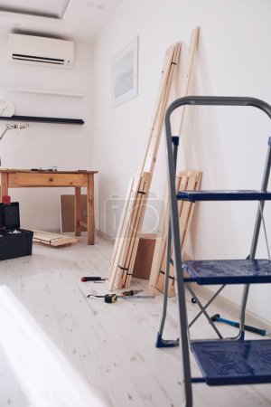 Téléchargez les photos : Table en bois rustique et matériel pour les nouvelles étagères dans un appartement moderne. - en image libre de droit