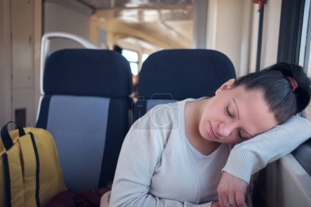 Foto de Mujer durmiendo en un asiento de tren mientras viaja. - Imagen libre de derechos