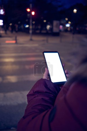 Foto de Mujer sosteniendo el teléfono celular y cruzando la calle. - Imagen libre de derechos