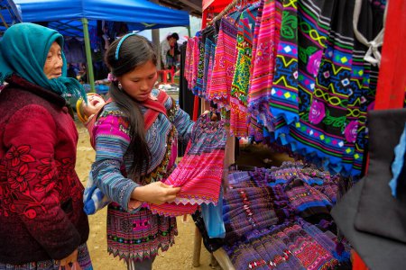 Téléchargez les photos : Can Cau, Vietnam - 17 décembre 2022 : Une femme achète une robe traditionnelle sur le marché de Can Cau dans la province de Lao Cai, Vietnam. - en image libre de droit