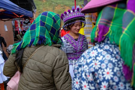 Téléchargez les photos : Can Cau, Vietnam - 17 décembre 2022 : Une femme essaie une robe traditionnelle sur le marché de Can Cau dans la province de Lao Cai, Vietnam. - en image libre de droit