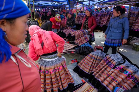 Téléchargez les photos : Bac Ha, Vietnam - décembre 18, 2022 : Femmes vendant des vêtements traditionnels au marché de Bac Ha au Vietnam. - en image libre de droit