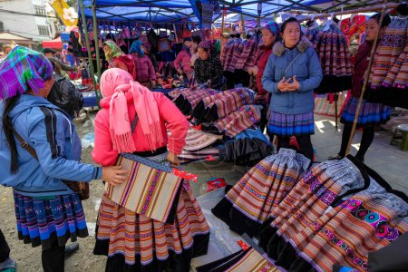 Téléchargez les photos : Bac Ha, Vietnam - décembre 18, 2022 : Femmes vendant des vêtements traditionnels au marché de Bac Ha au Vietnam. - en image libre de droit
