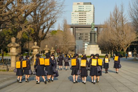 Téléchargez les photos : Tokyo, Japon - 7 mars 2023 : Filles en uniforme scolaire marchant près de la statue d'Omura Masujiro à Chiyoda, Tokyo, Japon. - en image libre de droit
