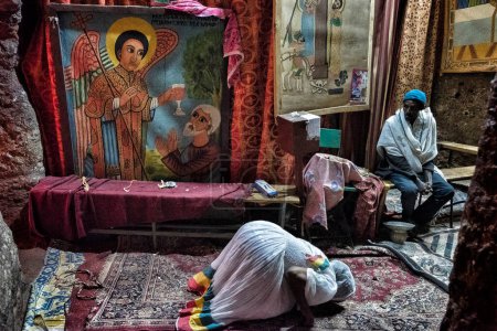 Téléchargez les photos : Lalibela, Éthiopie - 7 janvier 2018 : Une femme prie dans une église de Lalibela. Au cours des premiers jours de janvier, des milliers de pèlerins chrétiens orthodoxes éthiopiens se rendent dans la ville de Lalibela en Éthiopie. - en image libre de droit