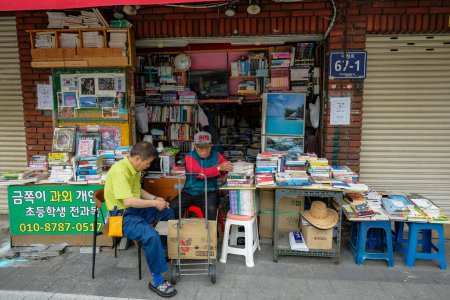 Photo for Busan, South Korea - May 26, 2023: Two men selling books on Bosu-dong Book Street, it is a famous book selling street in Busan, South Korea. - Royalty Free Image