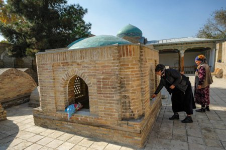 Téléchargez les photos : Kokand, Ouzbékistan - 24 octobre 2023 : Deux femmes font une offrande au mausolée Modari Khan de Kokand, dans la vallée de Fergana, en Ouzbékistan. - en image libre de droit