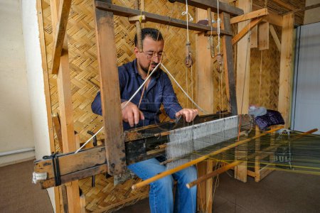 Téléchargez les photos : Kokand, Ouzbékistan - 25 octobre 2023 : Un artisan travaillant avec un métier à tisser dans un atelier à la mosquée Jami à Kokand dans la vallée de Fergana, Ouzbékistan. - en image libre de droit