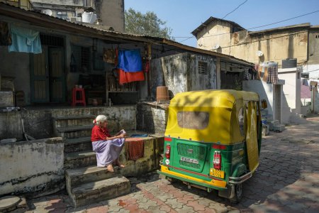 Téléchargez les photos : Ahmedabad, Inde - 12 janvier 2024 : Une femme assise à côté d'un autorickshaw à Ahmedabad, Gujarat, Inde. - en image libre de droit