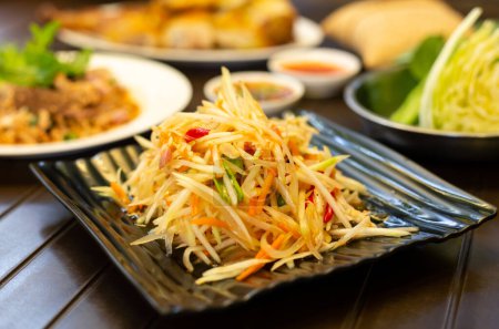 Téléchargez les photos : Salade thaïlandaise de papaye (Som Tum) sur une table en bois - en image libre de droit