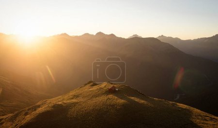 Photo for Sunset panorama of red idyllic remote lonely alpine mountain Brewster Hut perched on top of grass hill high up above Haast river valley, West Coast Southern Alps, South Island New Zealand - Royalty Free Image