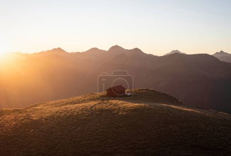 Photo for Sunset panorama of red idyllic remote lonely alpine mountain Brewster Hut perched on top of grass hill high up above Haast river valley, West Coast Southern Alps, South Island New Zealand - Royalty Free Image