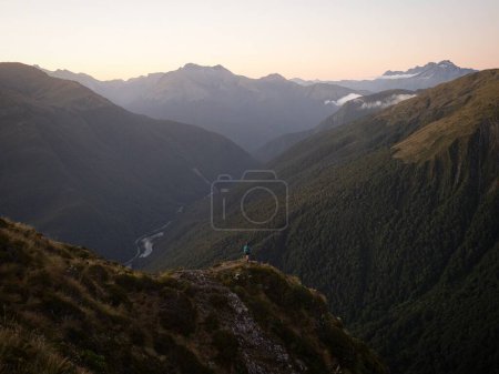 Photo for Young female woman hiking along scenic idyllic remote alpine mountain ridge path hill trail at Brewster Hut above Haast Valley, West Coast Southern Alps New Zealand - Royalty Free Image