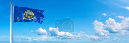Téléchargez les photos : Idaho flag - state of USA, flag waving on a blue sky in beautiful clouds - Horizontal banner - en image libre de droit