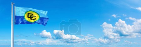 Téléchargez les photos : Communauté des Caraïbes Drapeau - état de l'Amérique, drapeau agitant sur un ciel bleu dans de beaux nuages - Bannière horizontale - en image libre de droit