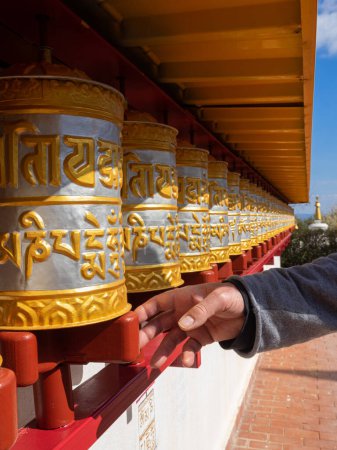 Photo for Man spinning prayer wheels. The wheels have thousands of mantras inside symbolizing the sound of love and compassion - Royalty Free Image